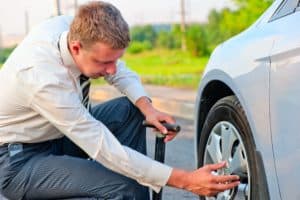 Businessman checks a defective car tire on a road in Alabama.