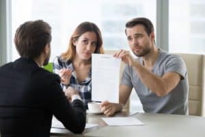 Young skeptical couple meet lawyer dissatisfied with terms of suspicious contract.