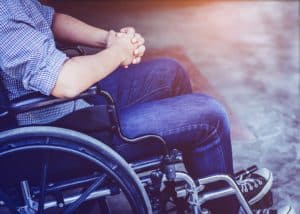 Paralyzed man praying on his wheelchair.