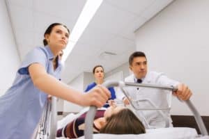 Doctors carrying unconscious woman on hospital gurney to the emergency room.