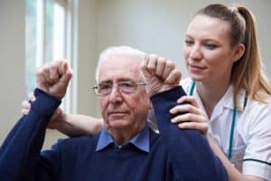 Nurse assessing stroke victim by raising arms.