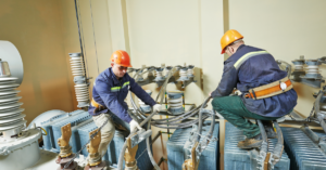 Electricians at huge power industrial transformer installation.