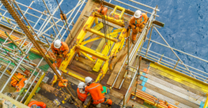 Offshore workers with full Personal Protective Equipment (PPE) performing maintenance.