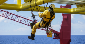 A commercial abseiler with fall arrestor device hanging on bridge pipeline structure.