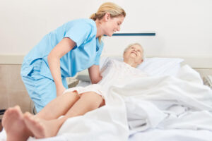 Nurse helps senior patient in nursing home into bed