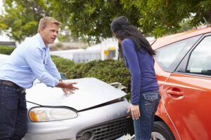 Angry driver talking to woman driver about car accident.