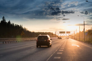 Cars in motion blur on highway during sunset.